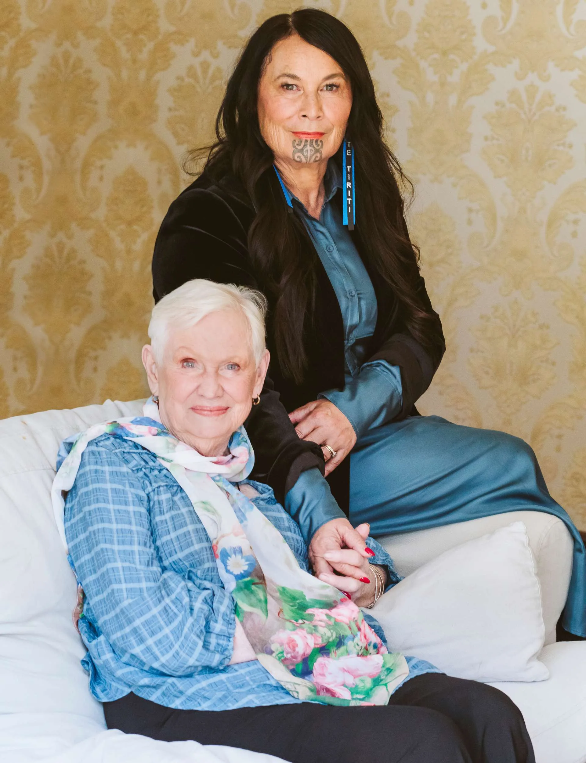 Debbie Ngarewa-Packer sitting on the arm of a couch beside mum, Colleen