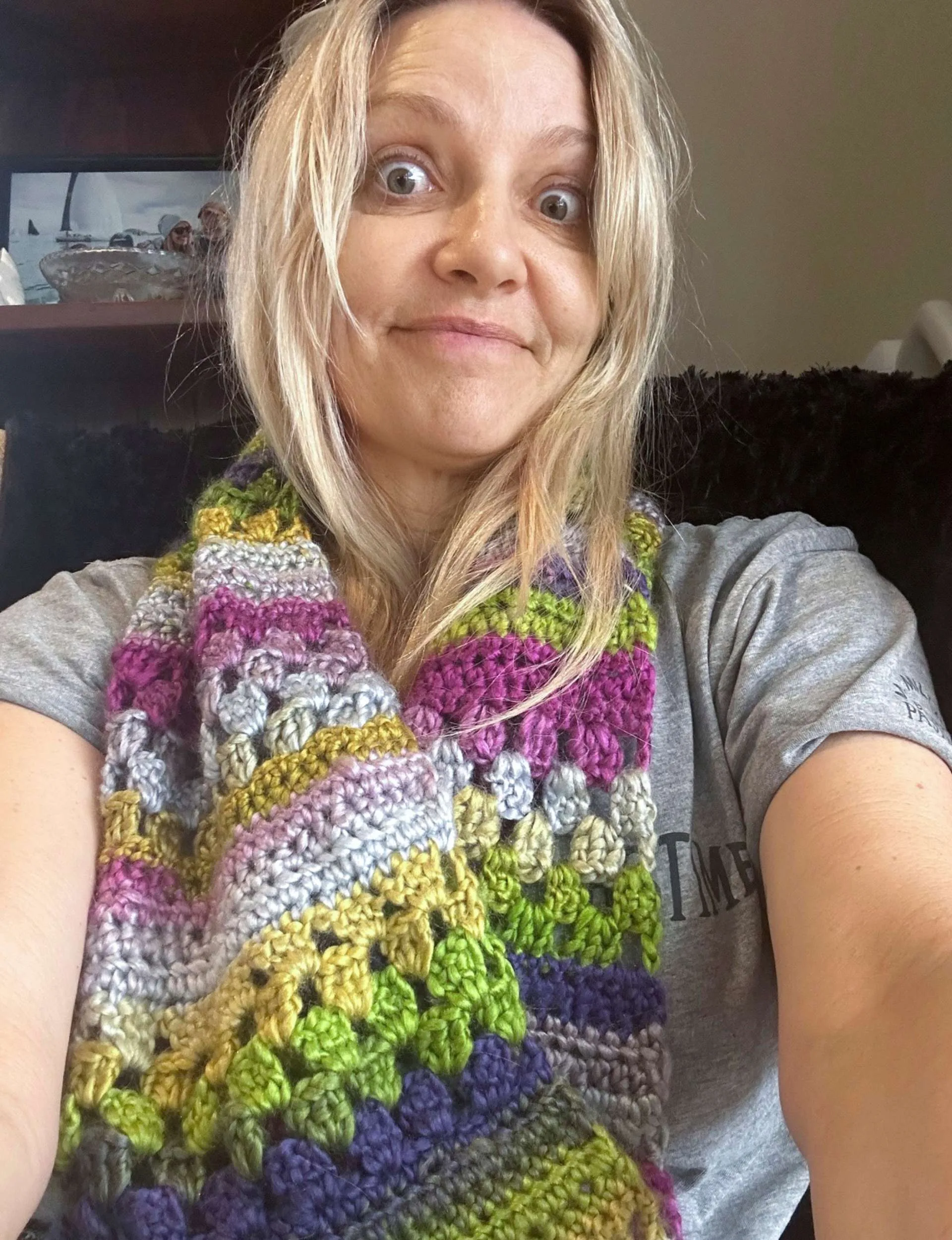 Mel wearing a purple, green, gold and white scarf she crocheted