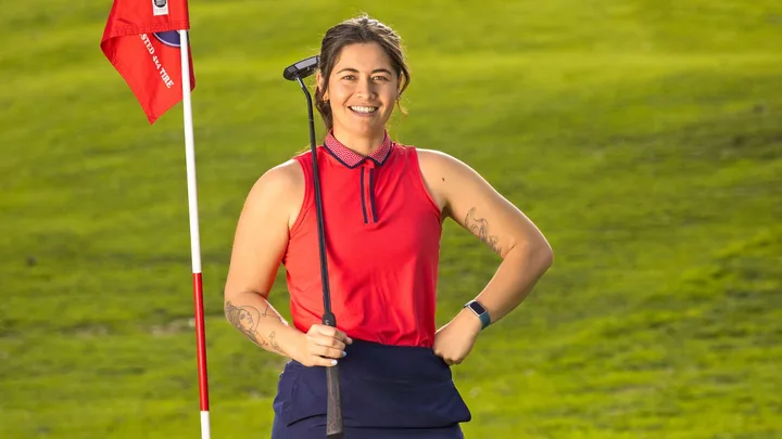 Nadine on the golf course, standing beside a flag