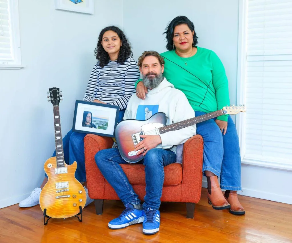 Otis' family sitting in his chair with his guitars and photo