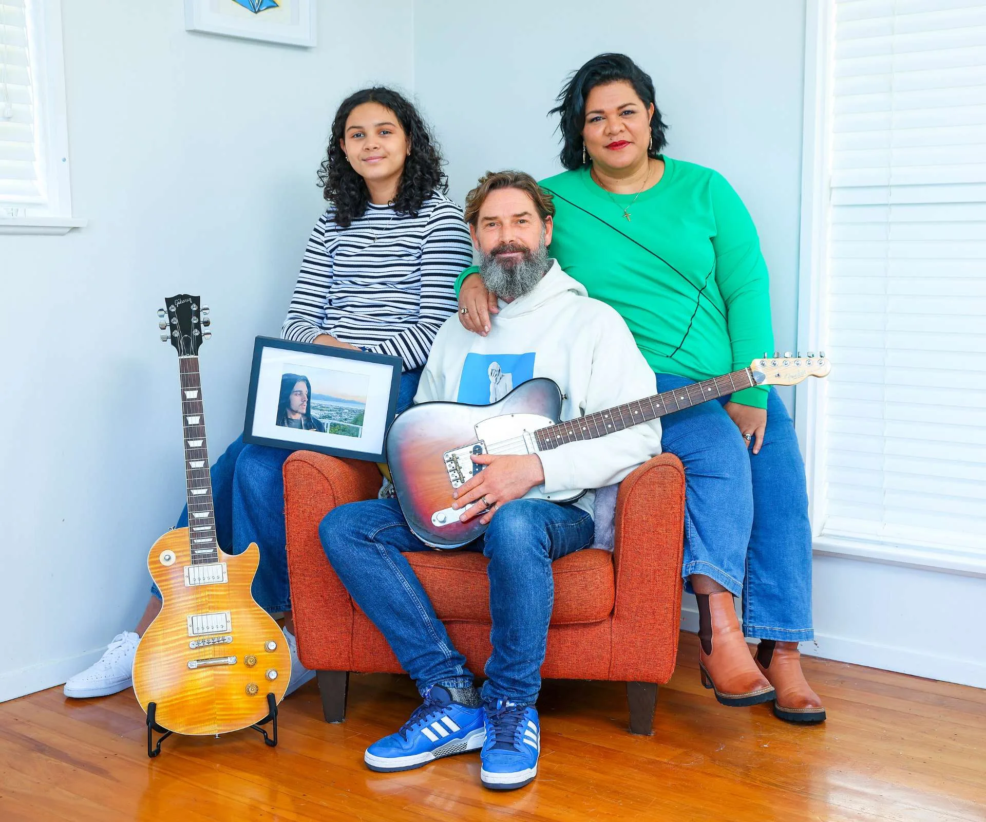 Otis' family sitting in his chair with his guitars and photo