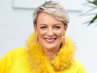 Lisa O'Neill smiling in a yellow furry collared shirt