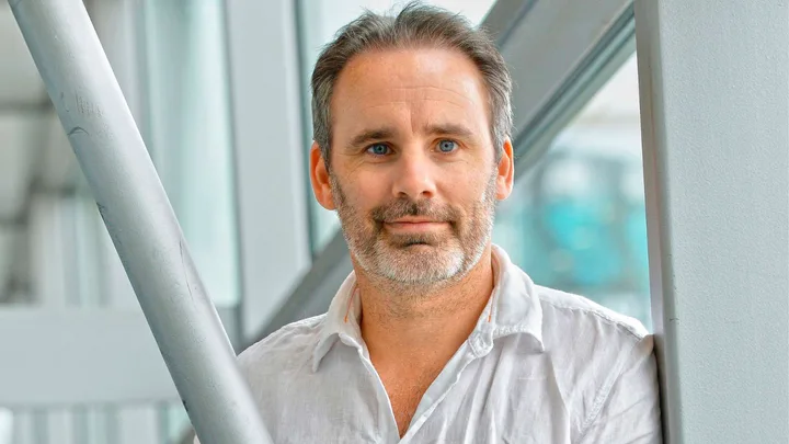 Paul Cleave standing to the side of a silver metal pole