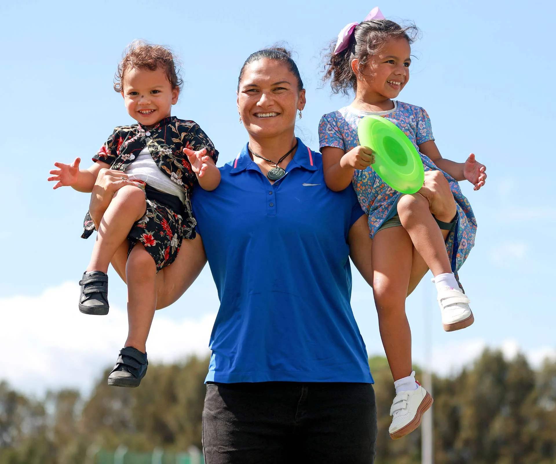 Valerie Adams holding each of her kids up on her biceps