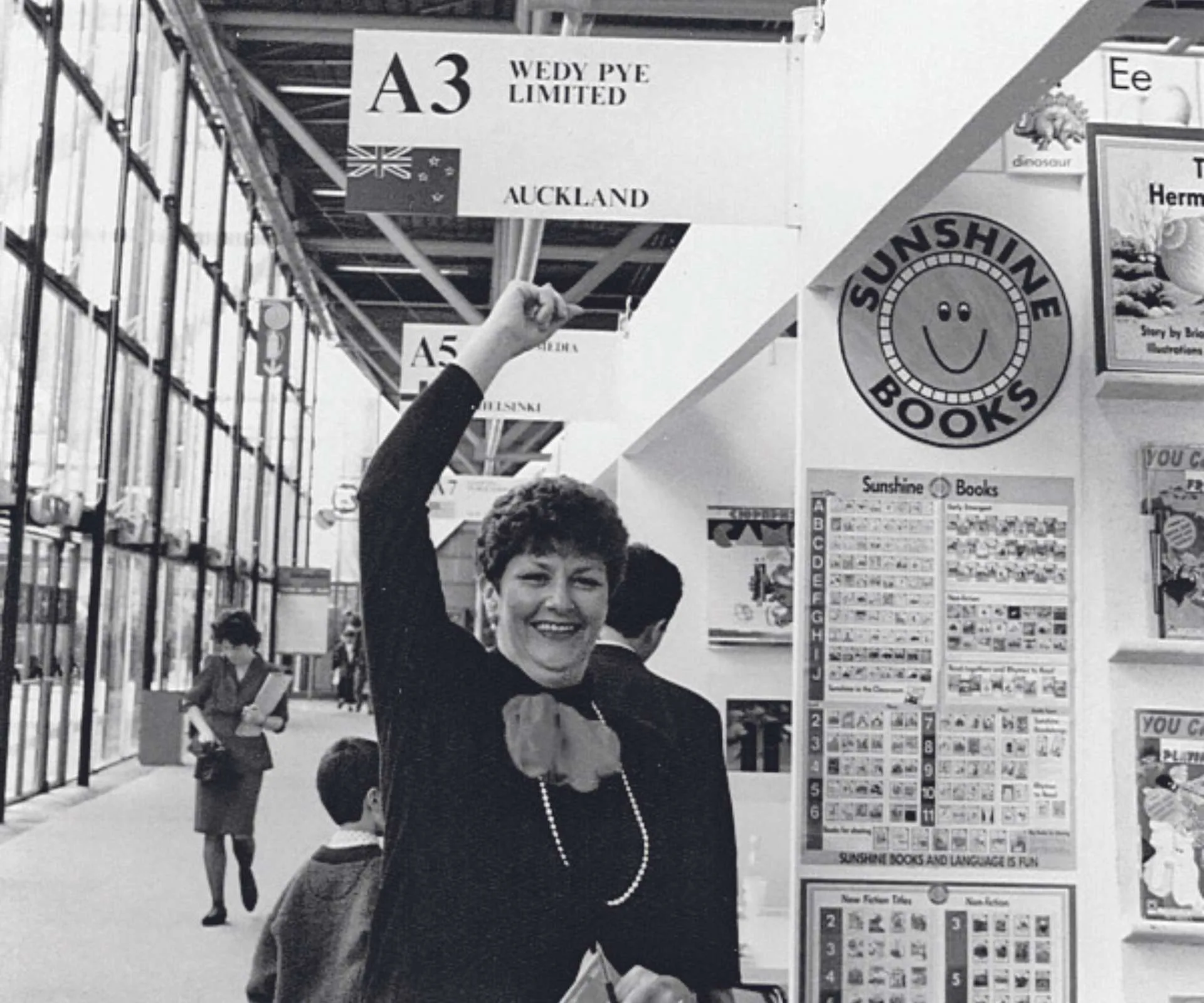 Dame Wendy Pye standing under a sign at a book fair with her name on it