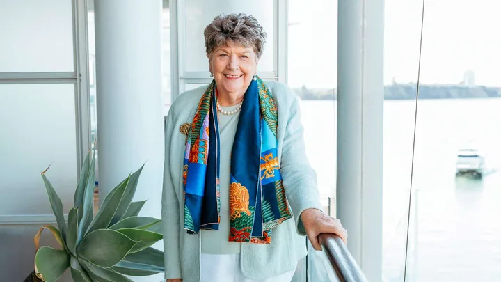 Dame Wendy Pye holding a rail in front of a window