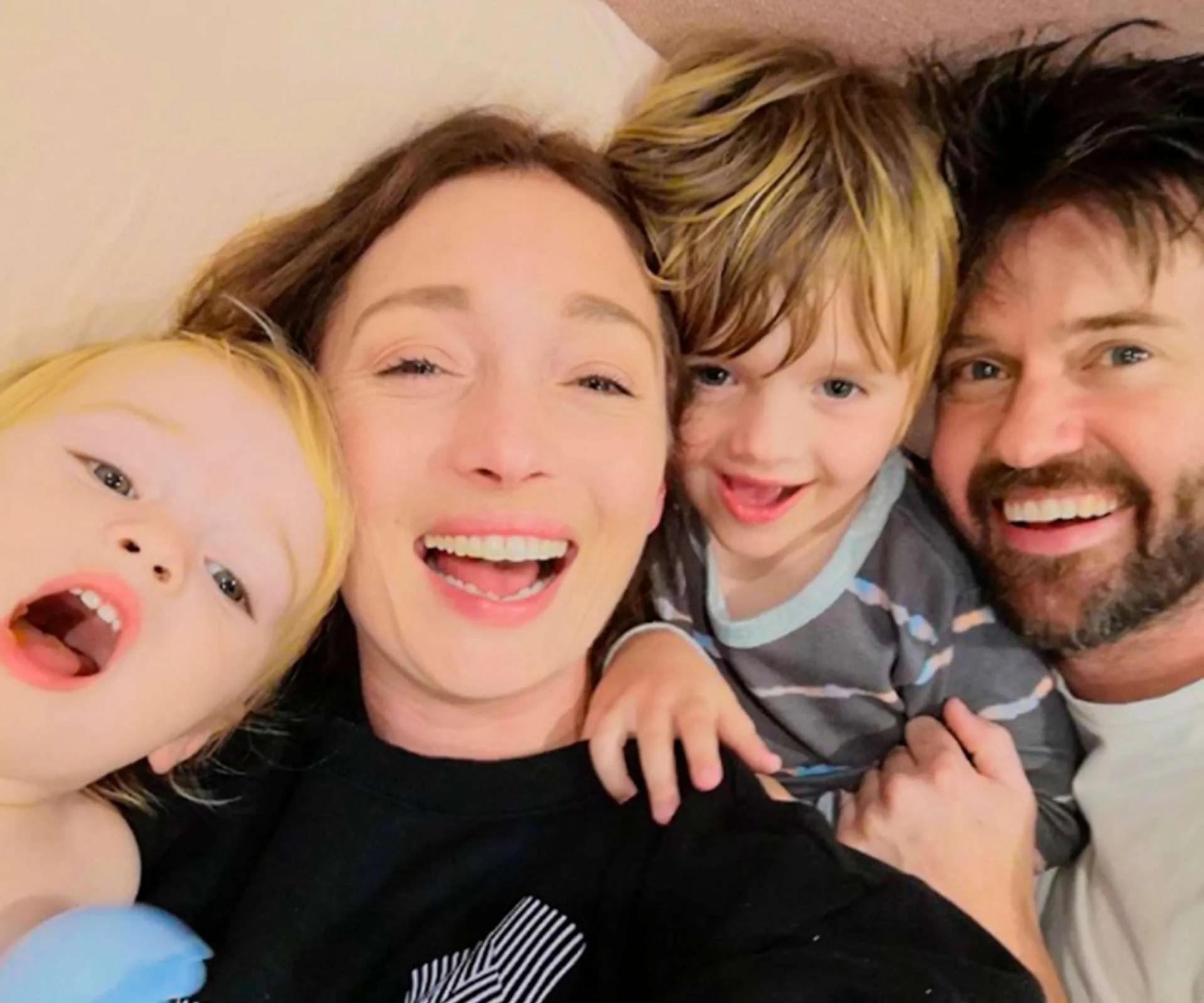 Laying in bed with her husband and kids, all laughing