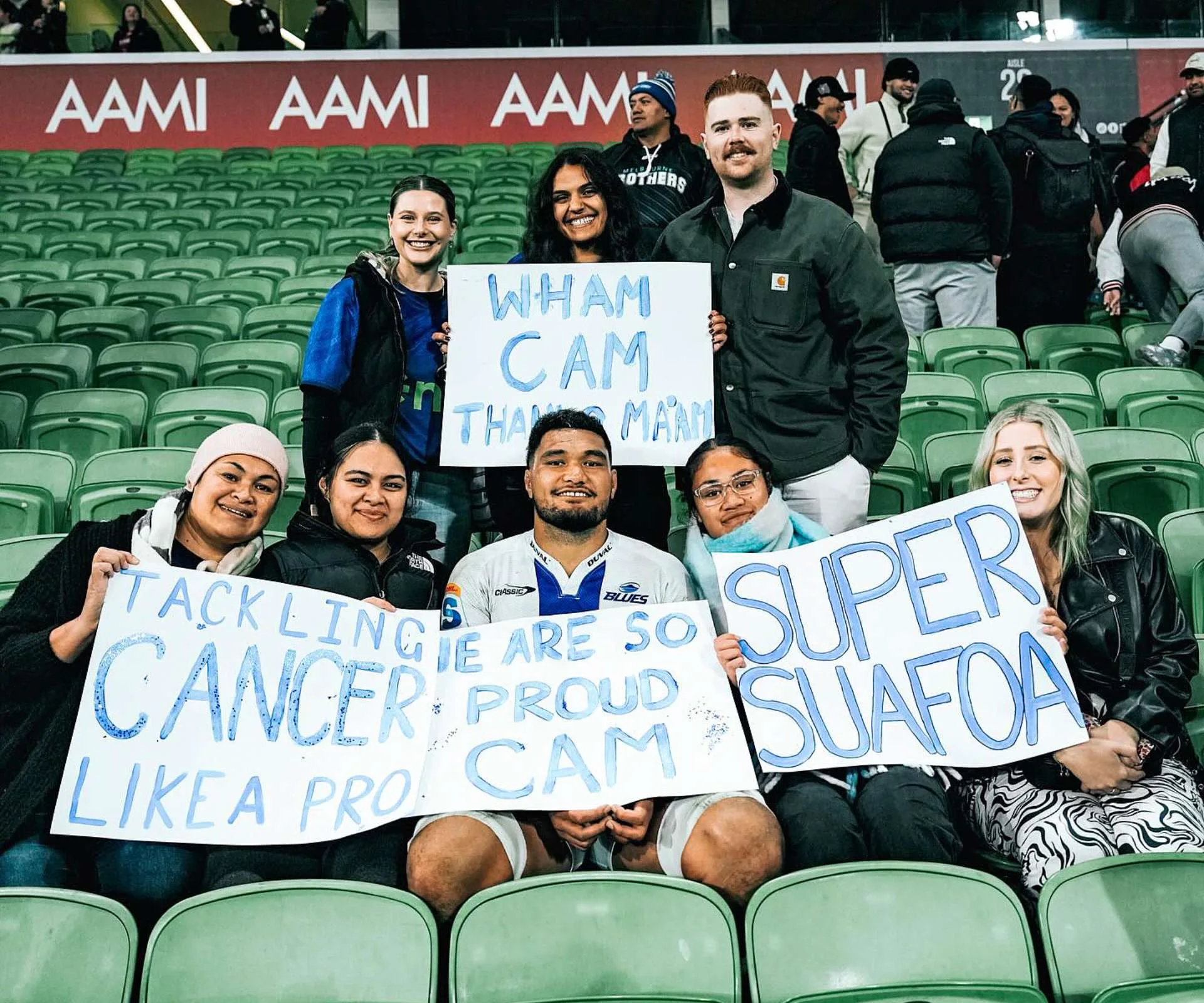 Family and friends holding up posters of pride and encouragement for Cameron during his cancer battle at a Blues game