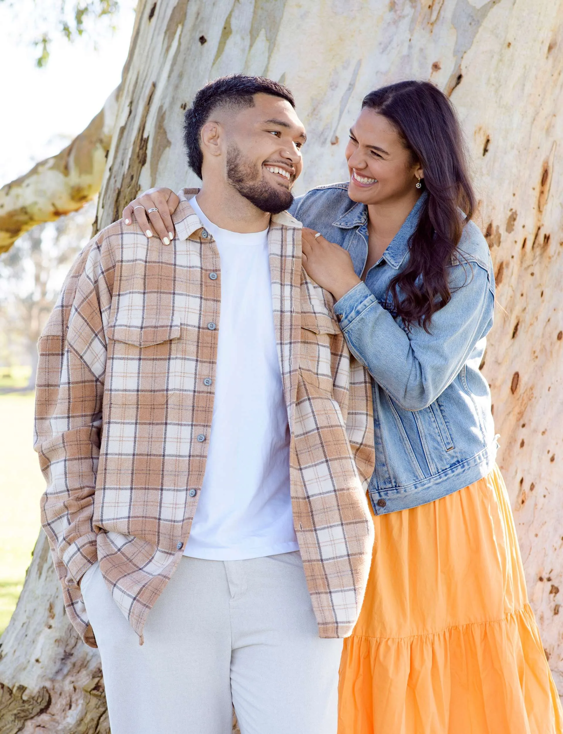 Britt laughing over Cameron's shoulder in front of a large tree trunk