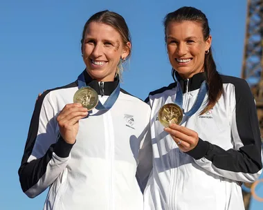 Brooke and Lucy holding up their 2024 Olympic medals in front of the Eiffel Tower