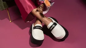 A model with her ankles crossed, wearing Crocs loafers