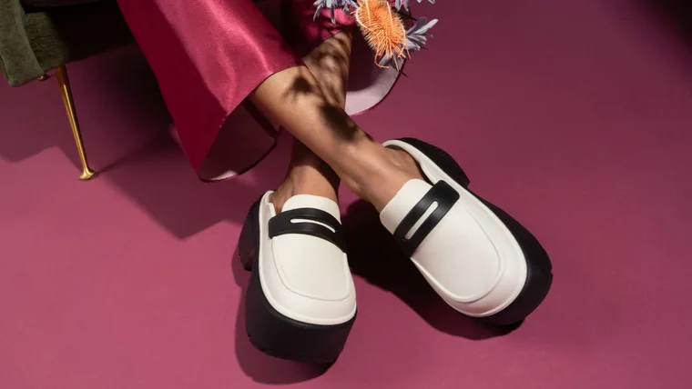 A model with her ankles crossed, wearing Crocs loafers