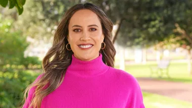 Courtney Tairi smiling in a fluro pink turtle neck