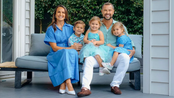 Sam Wallace siting on an outdoor couch surrounded by his family