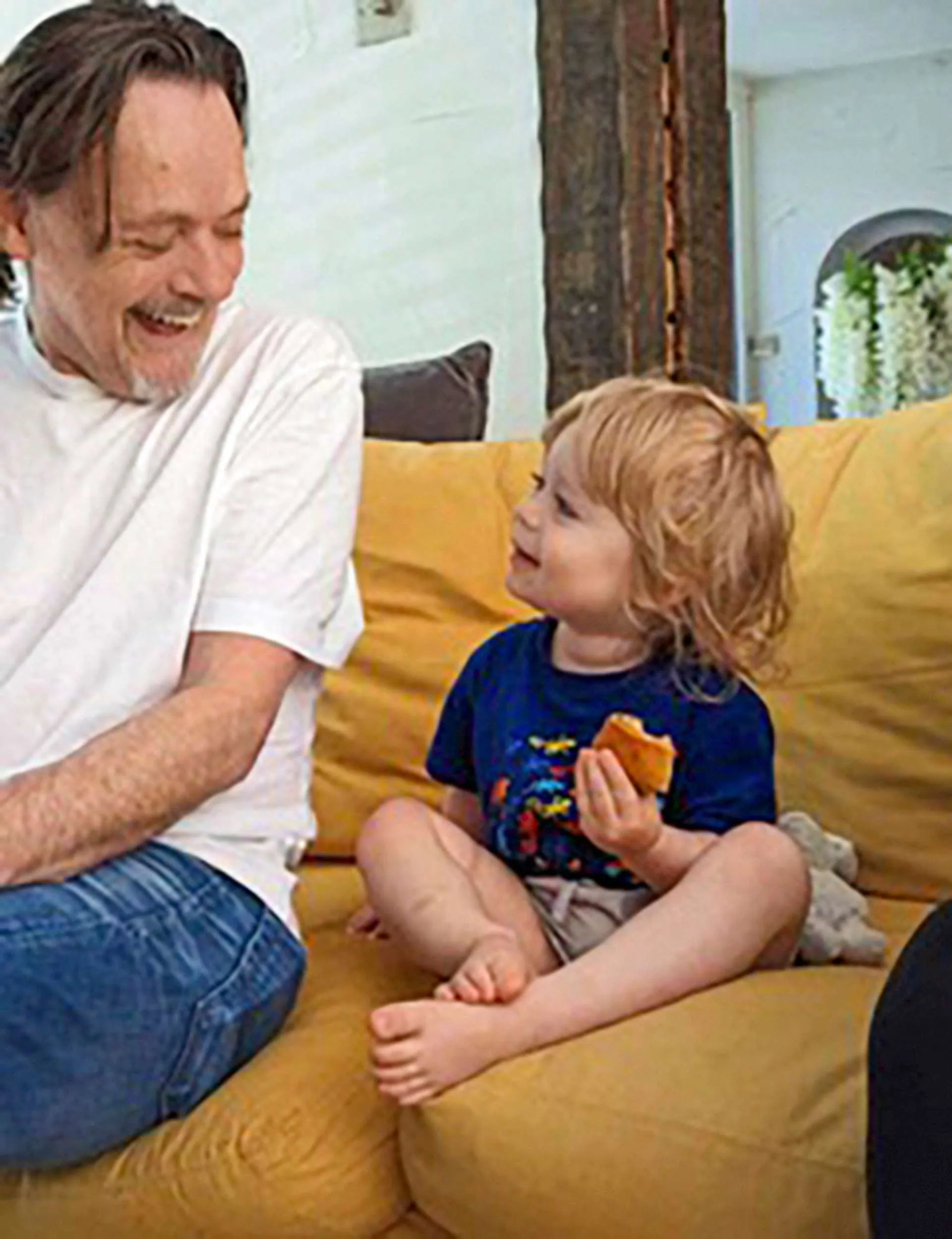Jimmy Brown sitting on a mustard couch with his grandson