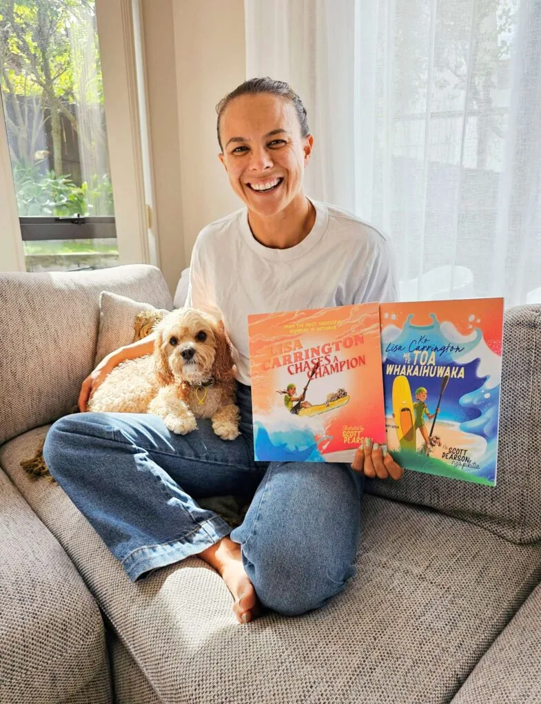 Lisa Carrington on a couch holding her children’s books