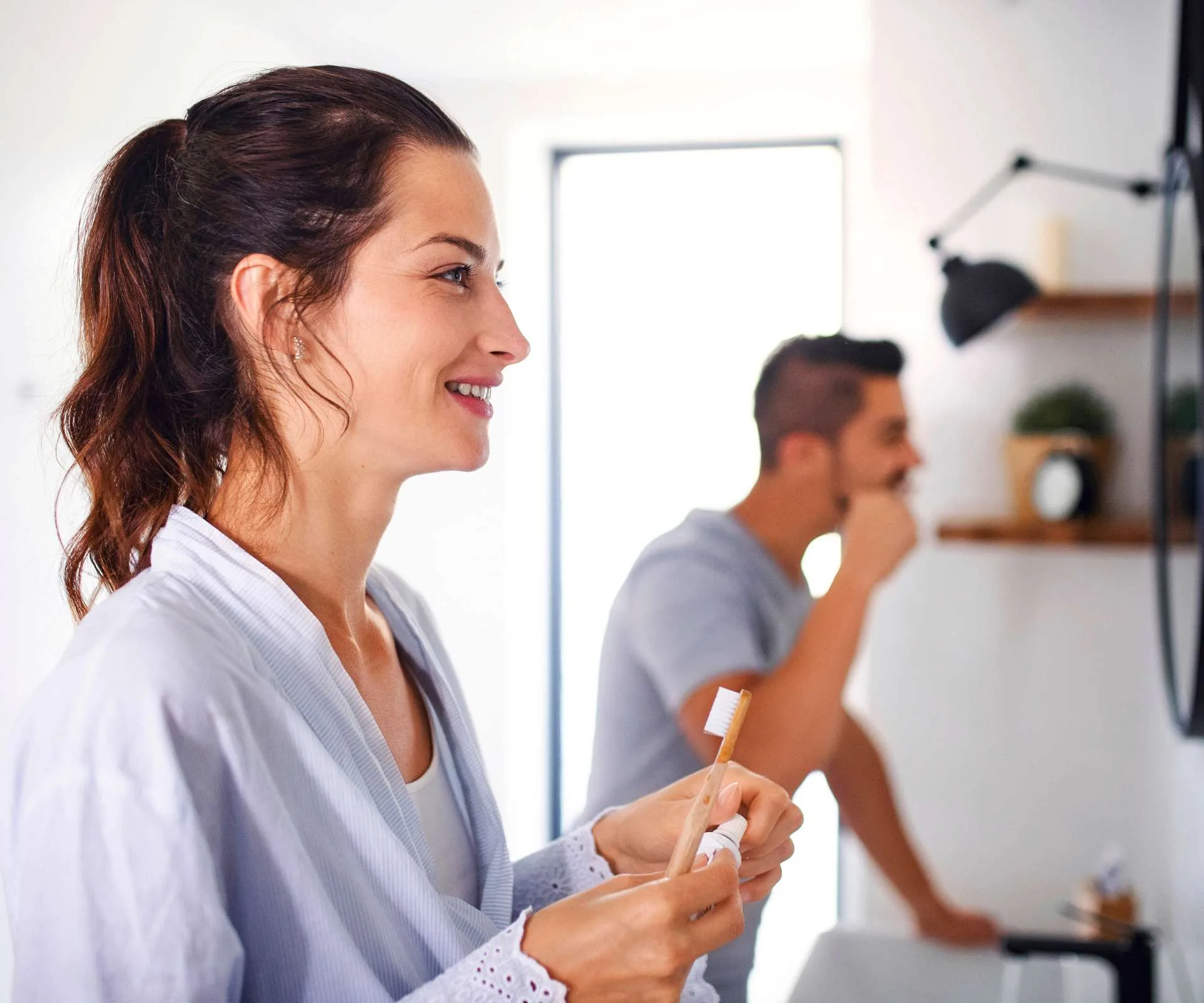 A couple brushing their teeth in the mirror to protect their dental care