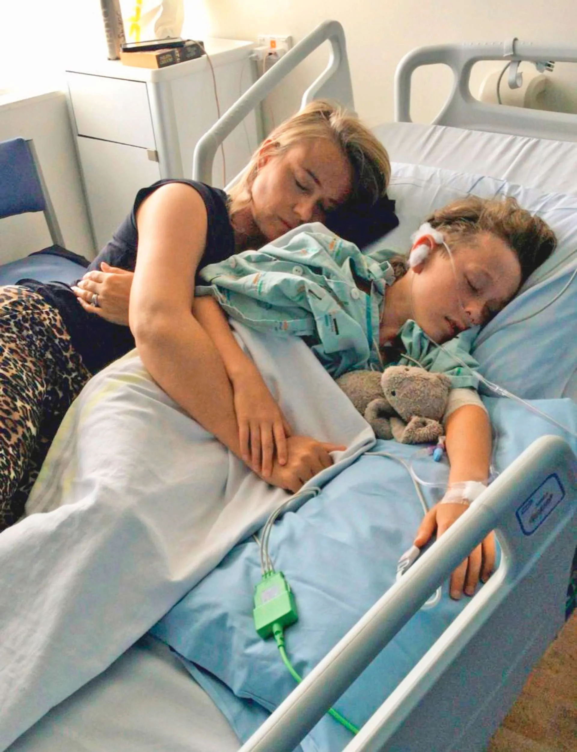 Jennifer laying in Cole's hospital bed with him