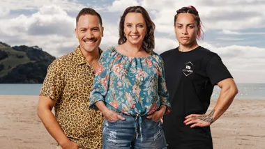 Three people smiling on a beach; one wears a leopard print shirt, another a floral blouse, and the third a black T-shirt.