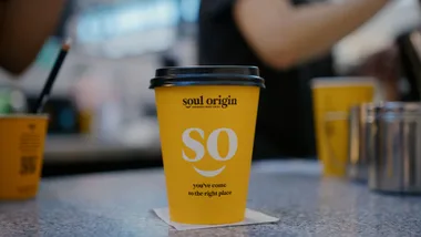 Yellow cup with "Soul Origin" logo and "SO, you've come to the right place" text on a counter.