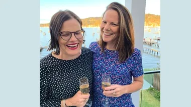 Briana and Alissa laughing with glasses of champagne