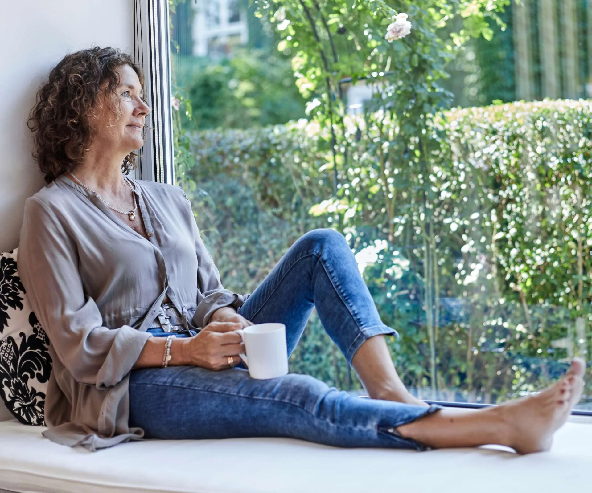A woman looking out of a window from a window seat because she is her own bestie