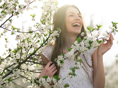 A woman standing amongst small white flowers wearing spring makeup