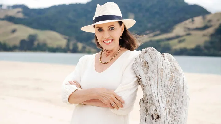 Suzanne Paul leaning on driftwood at the beach