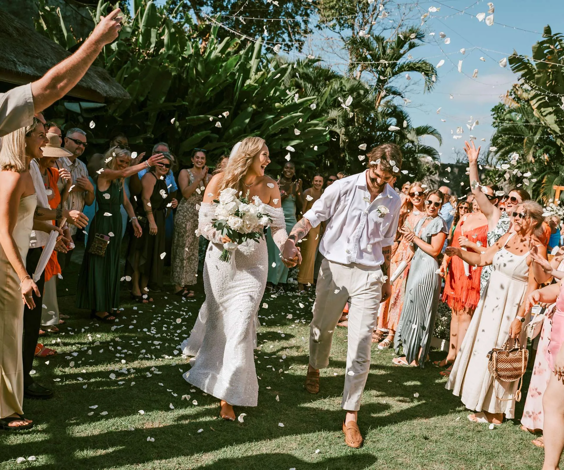 Brayden Inger and Georgina Fisher being showered in flower petals as they walk out of their wedding