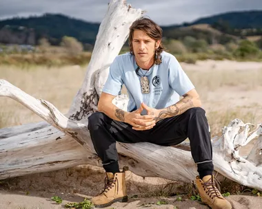 Vinnie sitting on a piece of driftwood on a beach