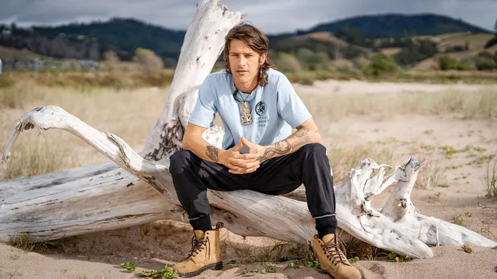 Vinnie sitting on a piece of driftwood on a beach