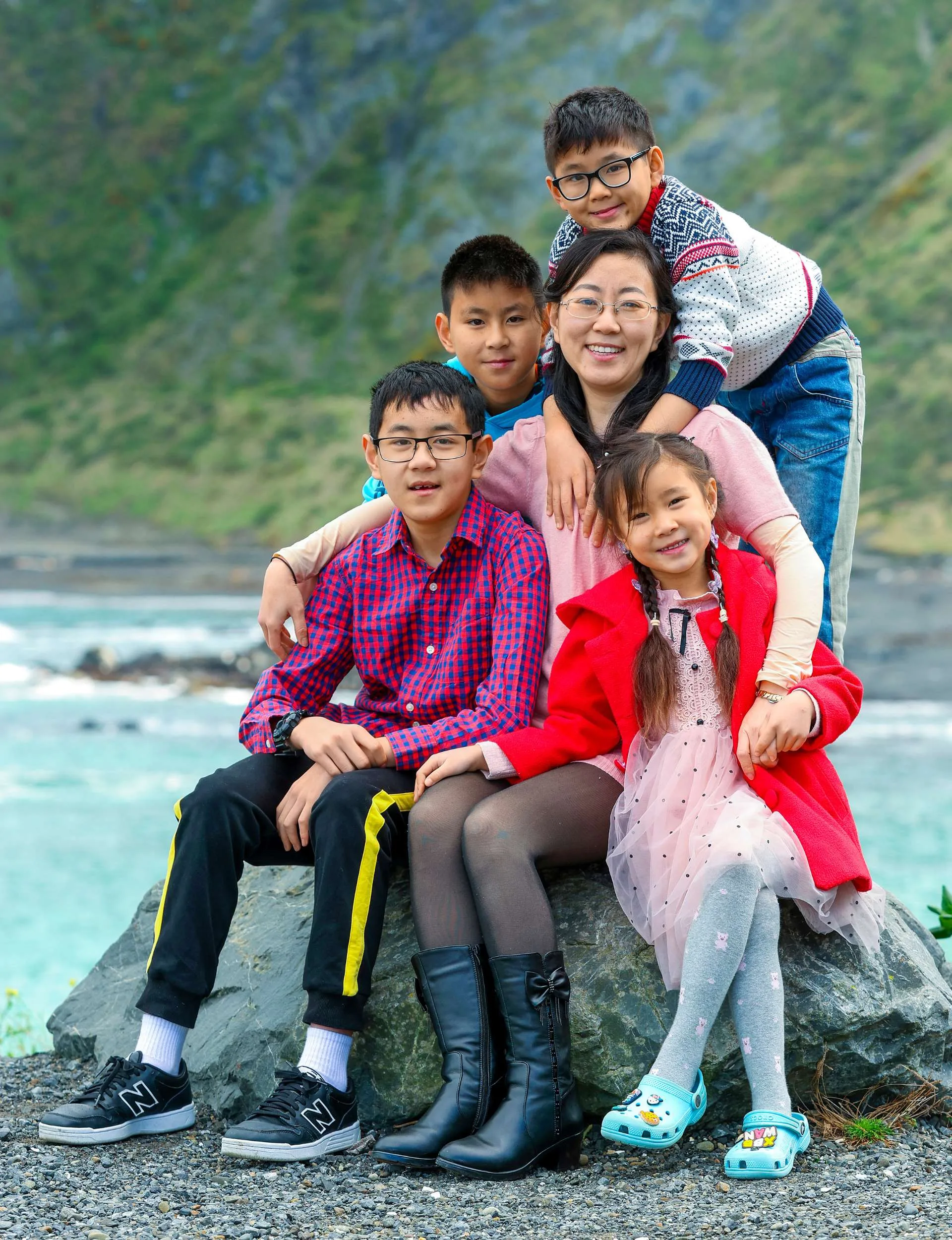 Alice Cai sitting on a boulder with her four kids around her