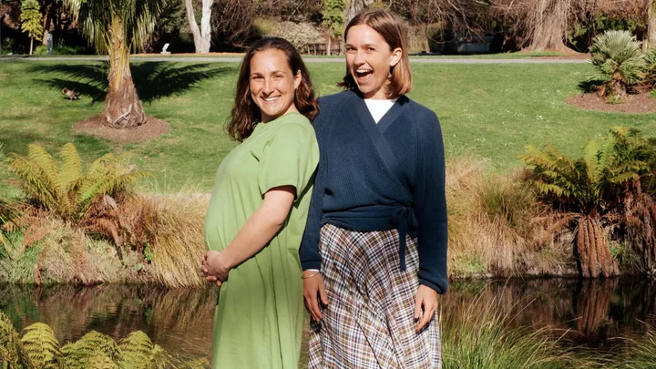 Two Raw Sisters Rosa and Margo in front of a river, Rosa cradling her baby bump