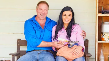 Claire and Andrew sitting on a bench while Claire feeds a baby kangaroo