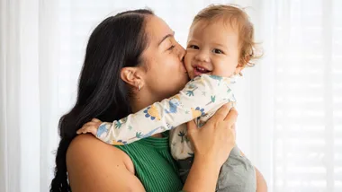 A Māori mother kissing her baby on the cheek