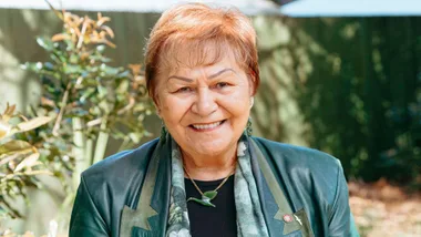 Dame Naida Glavish smiling in a green leather blazer