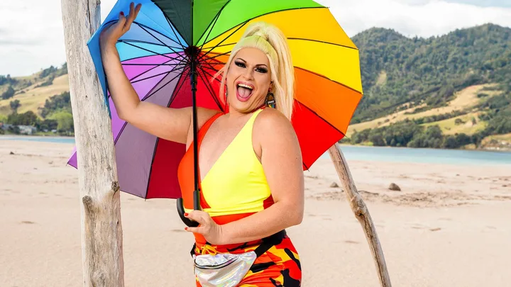 Spankie Jackzon with a rainbow umbrella on a beach for Celebrity Treasure Island