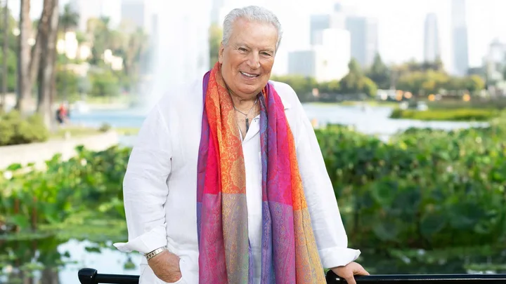 Richard Dalton wearing white with a colourful scarf on