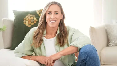 Emma Twigg sitting on the ground, leaning one elbow on the couch cushions