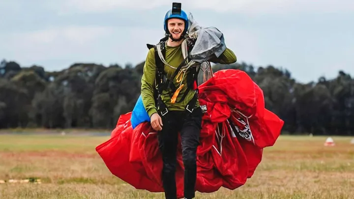 Liam Newman walking towards the camera with a parachute over his shoulder