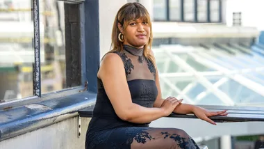 Manu Vaea in a black dress on a balcony