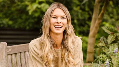 Chelsea Winter smiling while sitting on a wooden garden bench