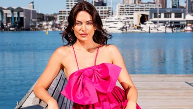 Katie Flood in a bright pink dress on the waterfront in Auckland