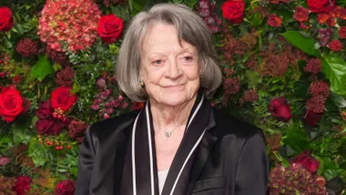 Dame Maggie Smith in front of a floral backdrop at an event