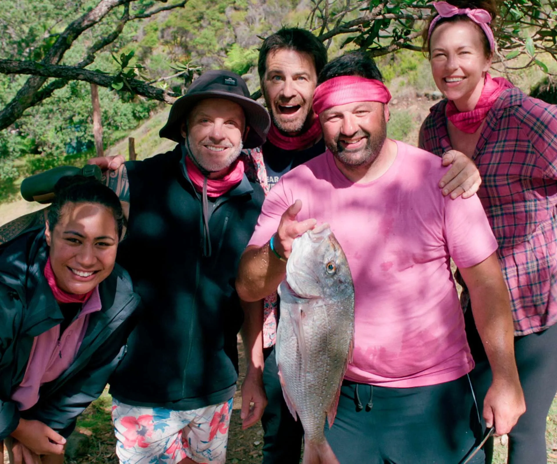 Proudly holding up his catch with his Celebrity Treasure Island teammates crowded around him
