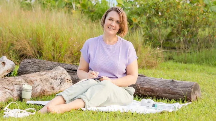 Kim Forrester sitting on a picnic rug in a field of grass