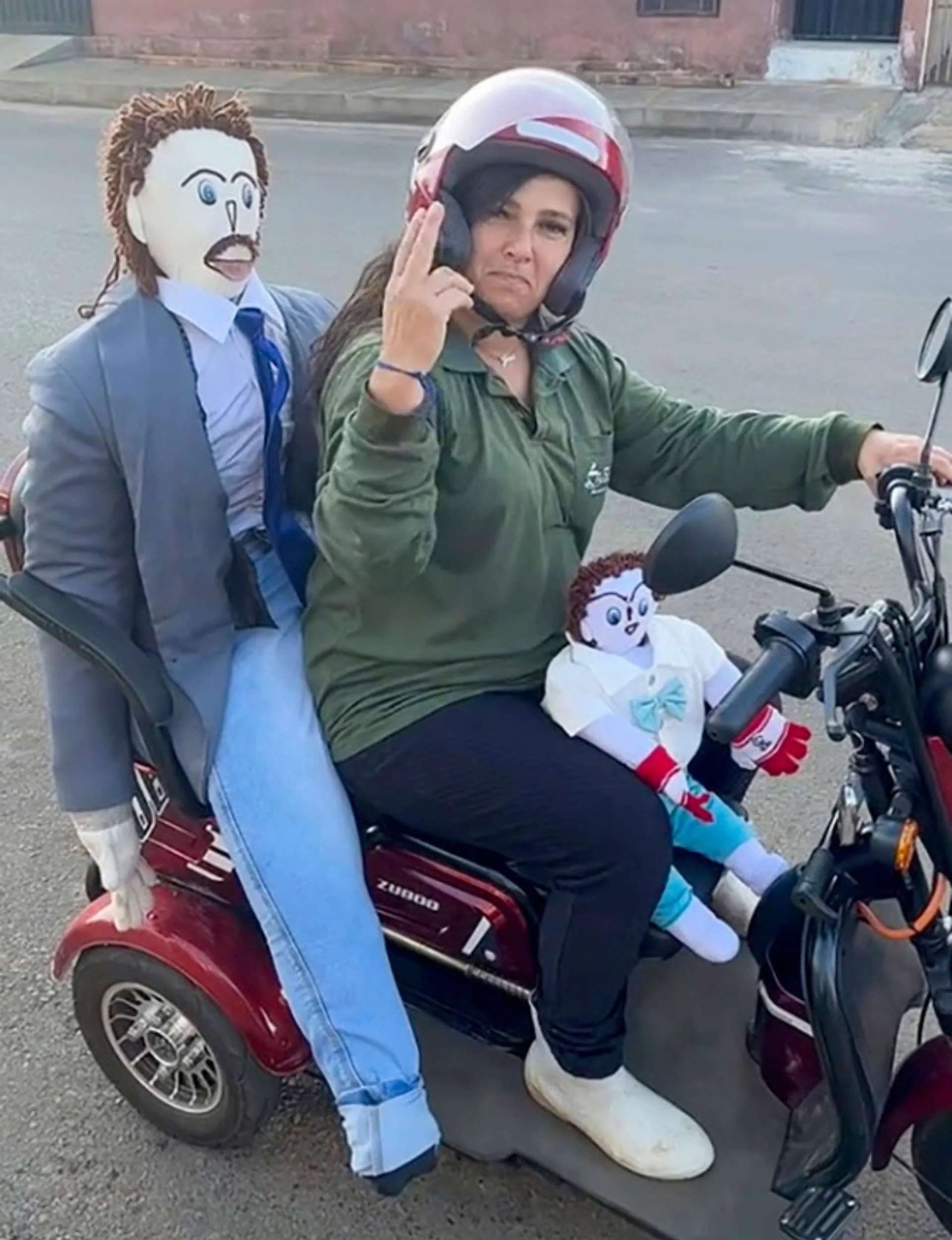 Meirivone Rocha driving a moped with her ragdoll husband behind her and her first son siting between her legs
