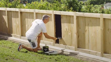 Man painting fence in black