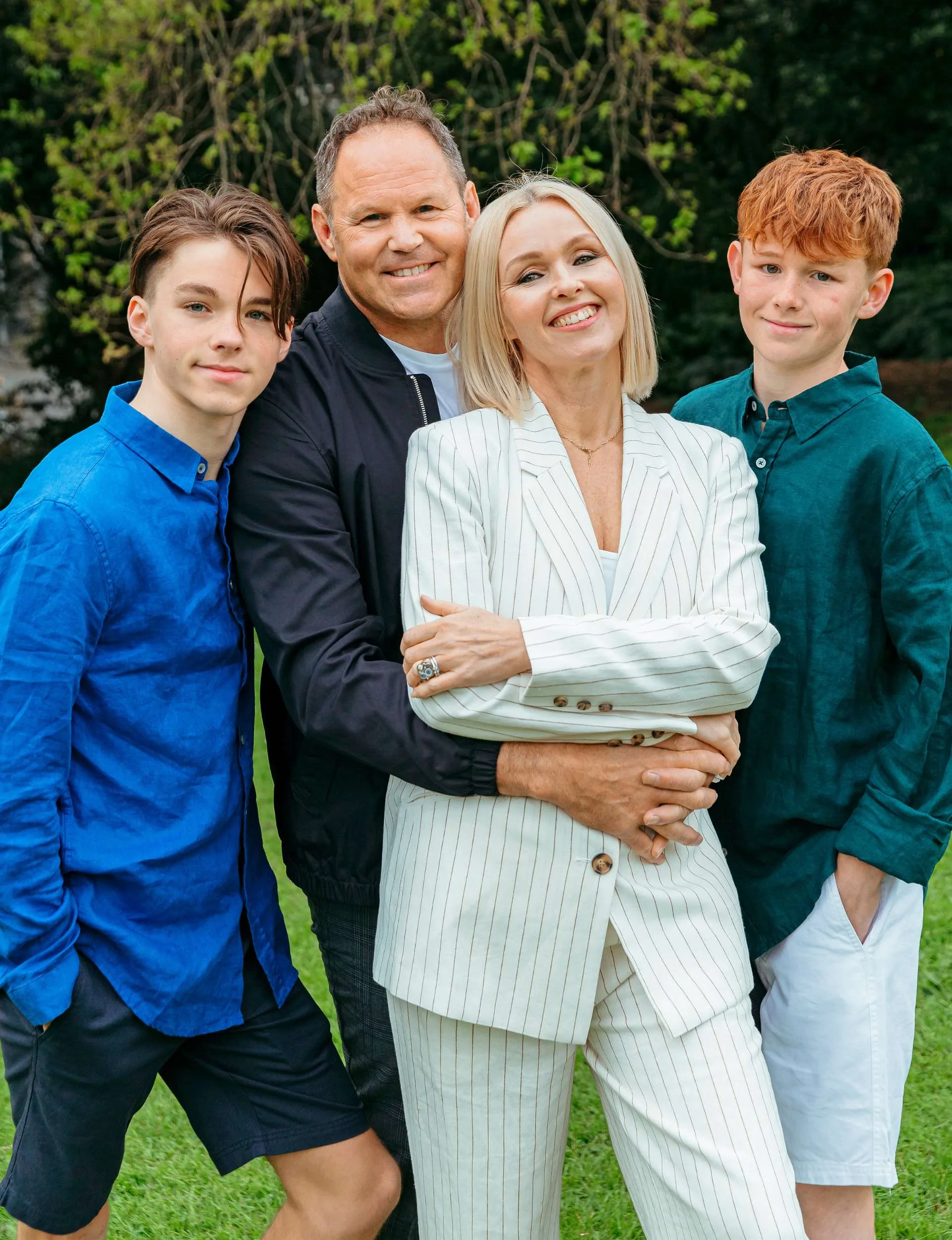 Josh Kronfeld standing with his wife and two sons in a park