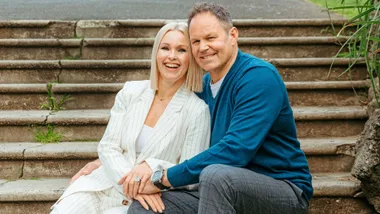 Josh Kronfield sitting on outdoor steps with his wife, Bronwyn